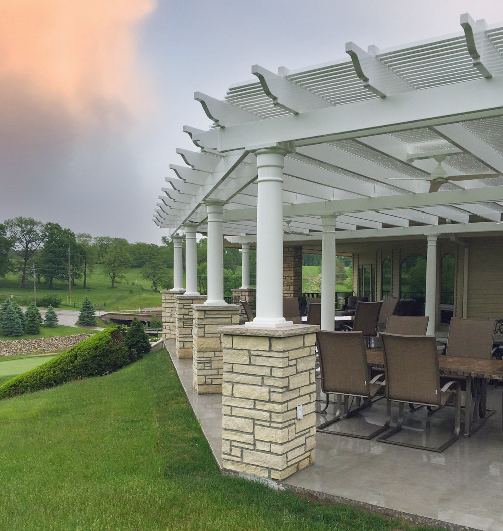 large patio area at golf course clubhouse covered by a pergola overhead