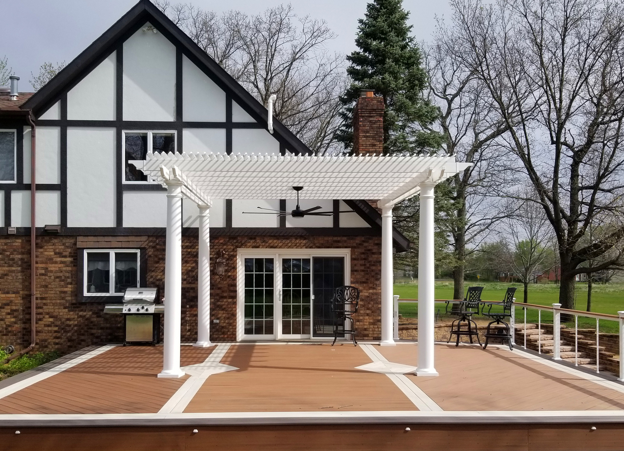 white pergola on a deck with outdoor fan