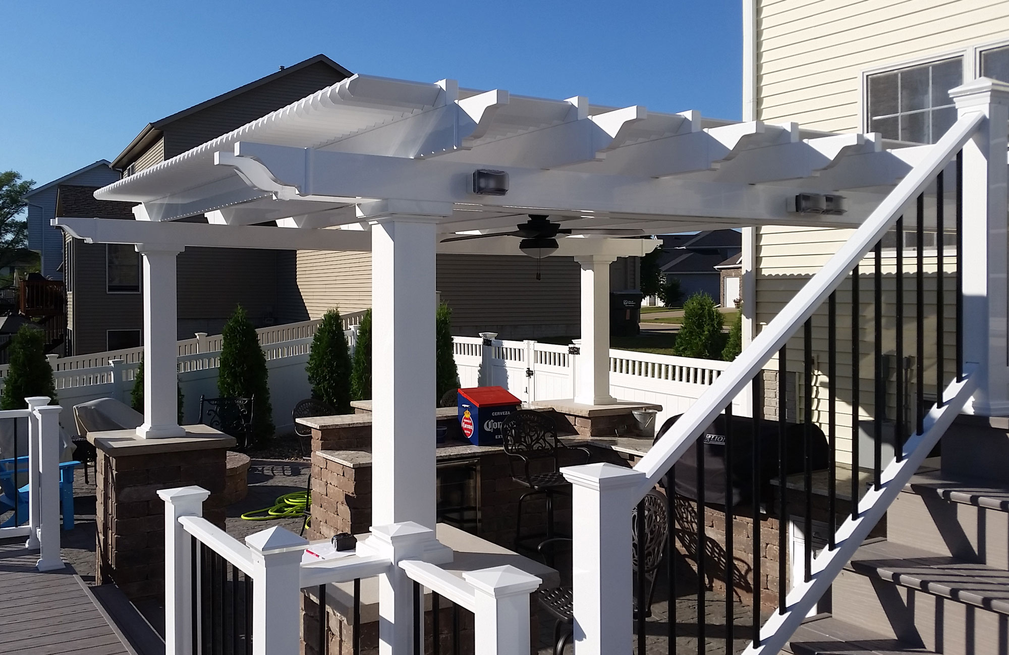White vinyl pergola on landscape columns over an outdoor kitchen and bar